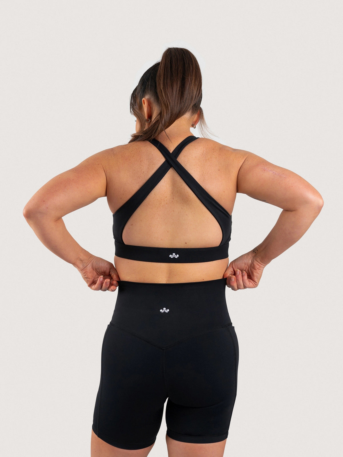 Back view of the Aella Storm Hybrid Shorts and Sports Bra in Black.