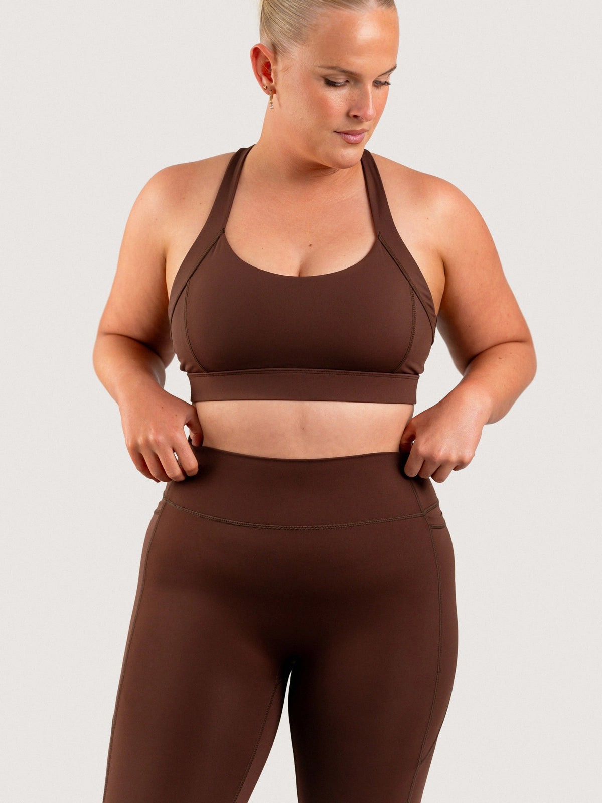 Close view of the high waistband on the Aella Storm Hybrid Leggings in Espresso, worn with the matching Sports Bra.